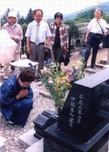 写真　千代子の墓前で手を合わせる澤地さん